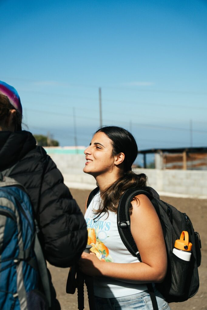 Woman with backpack hiking Acatenango, smiling in the sun. Volcanic adventure.