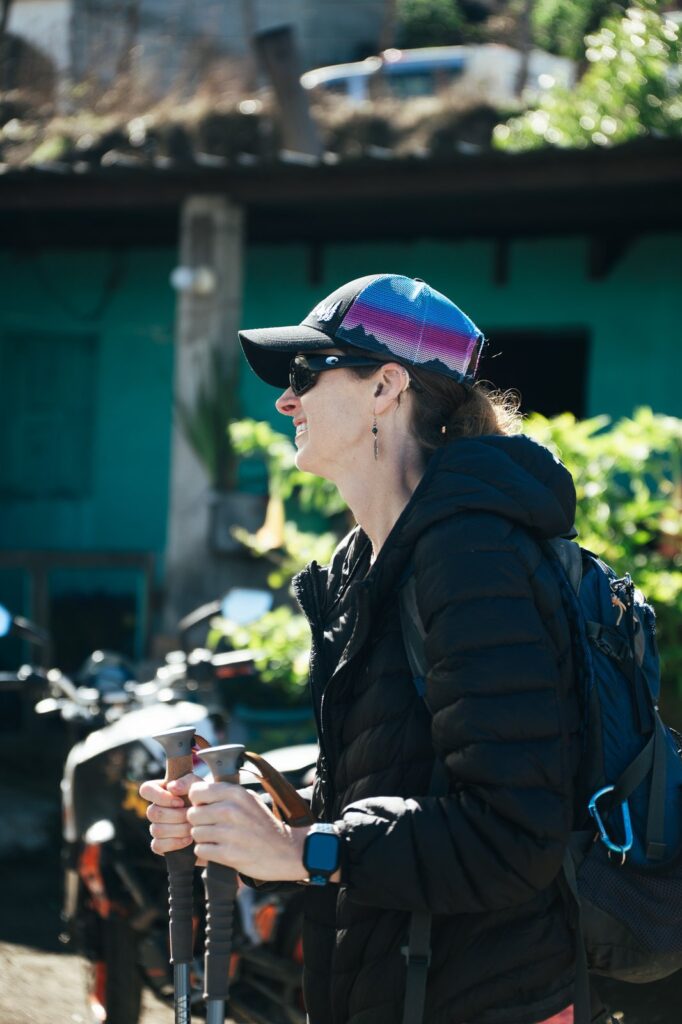 Hiker with trekking poles, ready for Acatenango Volcano, wearing a cap and backpack.