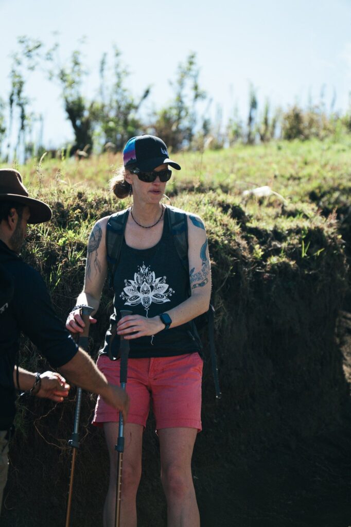 Woman hiking Acatenango Volcano with trekking poles, wearing sunglasses and a hat.