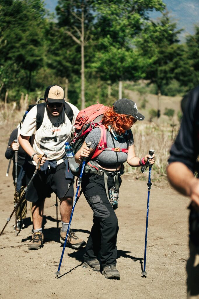 Hikers on Acatenango Volcano trail, using trekking poles, wearing backpacks.