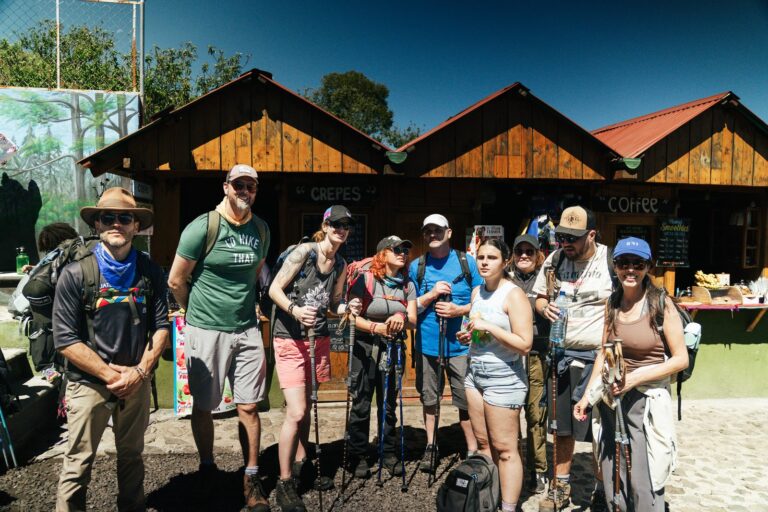 Group of hikers preparing for Acatenango Volcano hike, posing in front of food stalls.