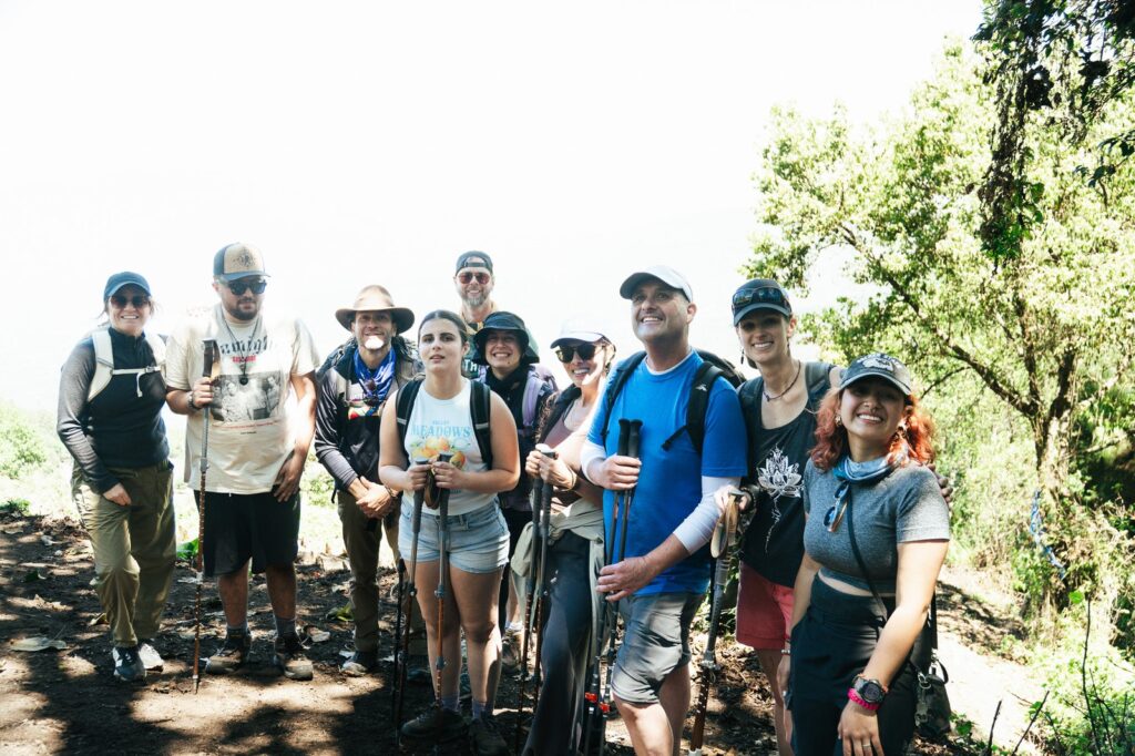 Group of hikers on Acatenango Volcano trail, wearing hats and using hiking poles.