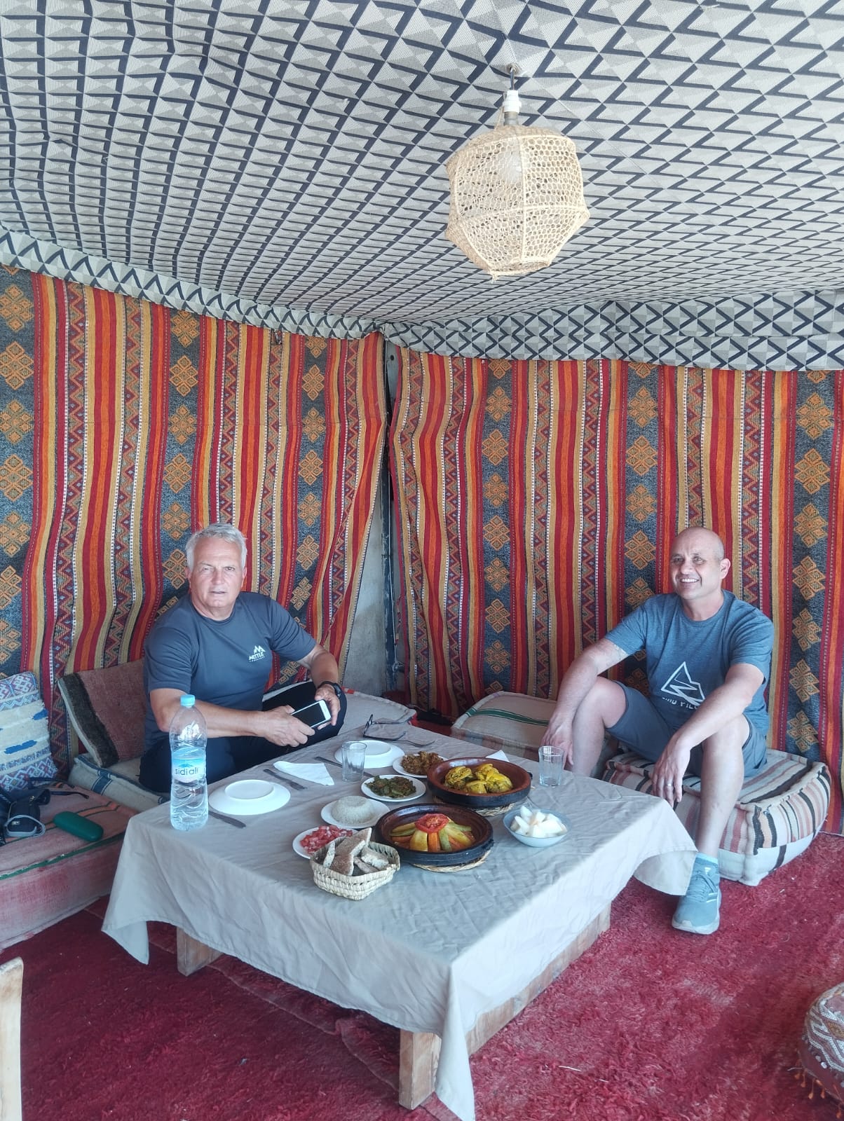 Two men enjoying a Moroccan meal in a traditional desert tent.