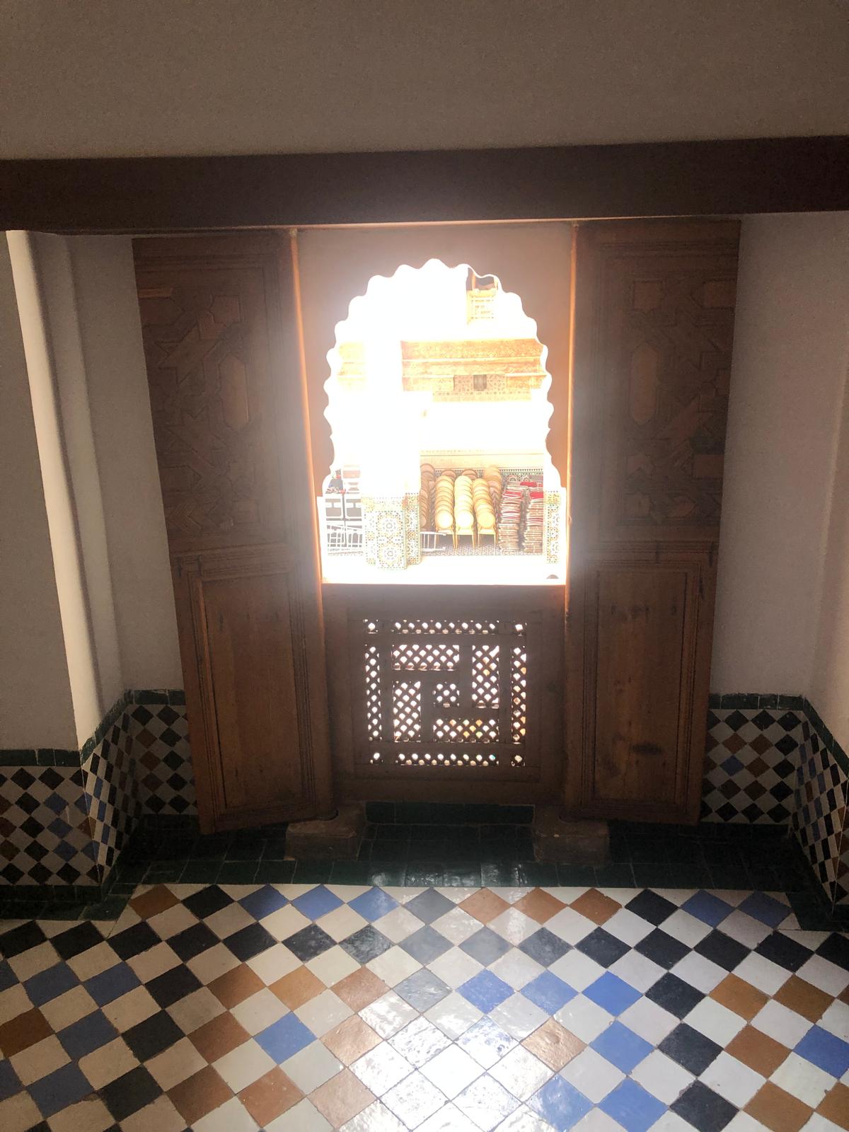 Ornate wooden window frame with geometric carvings and a tiled floor in Morocco