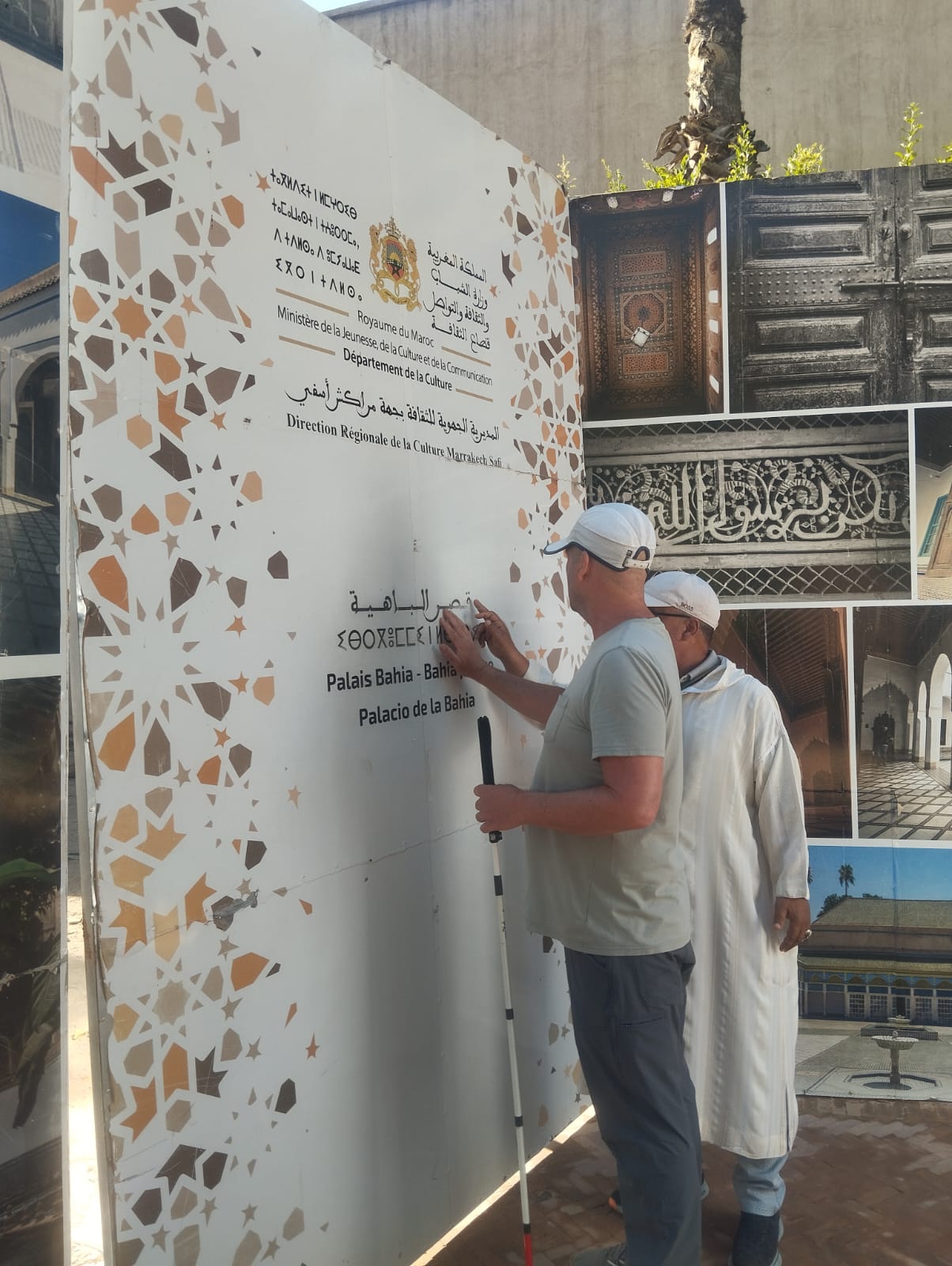 Two men look at a sign for Palais Bahia, Marrakech, Morocco